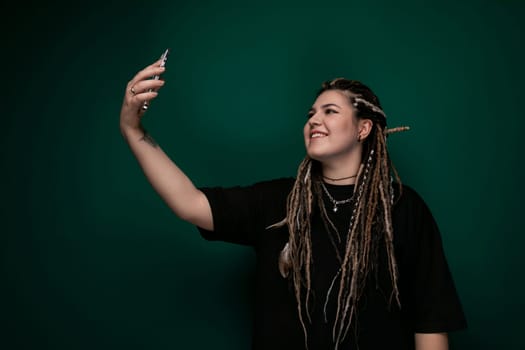 A woman with dreadlocks is seen holding a cell phone in her hand. She appears focused as she interacts with the device. Her distinctive hairstyle adds to her unique appearance.