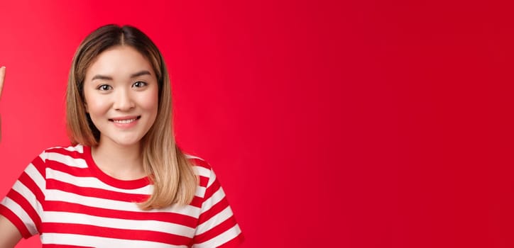 Close-up cheerful glad young attractive blond woman wear striped t-shirt smiling friendly make order, reservation for two show victory peace sign, stand red background, wanna be second.
