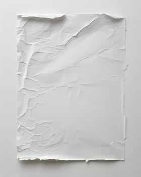 A crumpled rectangle of white paper, a natural material, rests on a white surface. This paper artifact can be used in creative arts or fashion as a transparent silver accessory