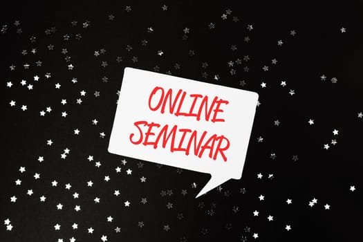 A white and red sign with the words Online Seminar written in red. The sign is surrounded by a star pattern