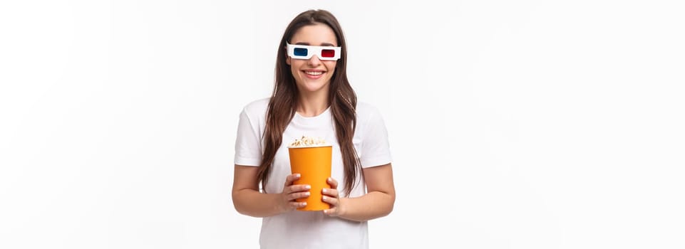 Entertainment, fun and holidays concept. Portrait of happy, joyful young girl enjoying watching awesome movie, premier night, wearing 3d glasses, smiling, eating popcorn, attend cinema.