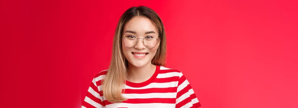 Close-up cheerful asian blond girl wear glasses smiling pleasant, give friendly toothy grin camera talking casually friends, standing happy show positive pleasant emotion, stand red background.