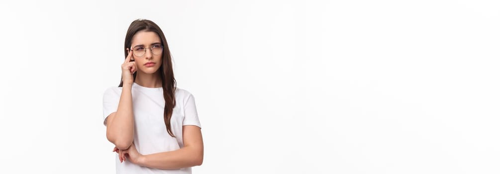 Waist-up portrait of doubtful attractive brunette girl looking focused and suspicious, thinking squinting and looking away while processing information with disbelief and doubt, white background.