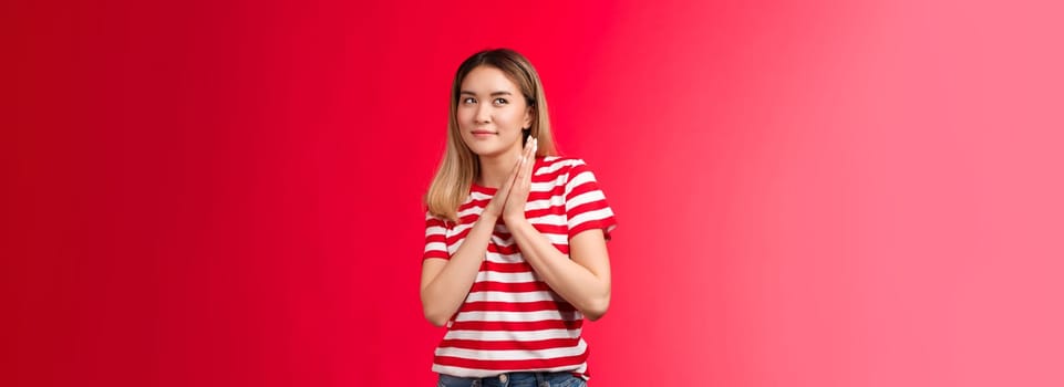 Smart and creative good-looking blond asian girl rubbing palms together devious and cunning have perfect plan, woman smirking curiously look up scheming have idea, stand red background.