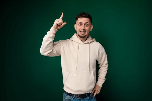 A man wearing a white hoodie is pointing directly at the camera. His gesture is assertive and direct, drawing attention to himself as the main subject of the photo.