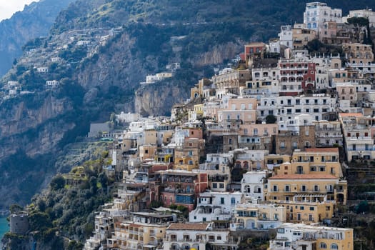 Beautiful view of residential colorful houses on mountain cliffs with green trees on a summer sunny day in Positano, Italy, close-up side view.