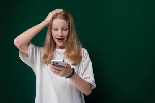 A woman is seen holding a cell phone in her hand and looking at the screen with a focused expression. She appears engaged in the content displayed on the device.