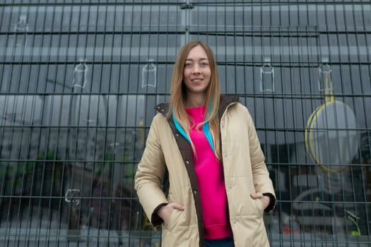 A woman stands confidently in front of a tall, modern building. She is dressed in professional attire and appears to be looking ahead.