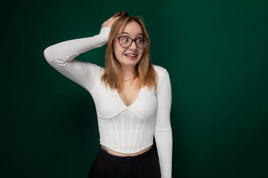 A woman wearing glasses is standing in a pose for a photograph. She is looking directly at the camera with a slight smile. Her hands are placed on her hips as she strikes a confident pose.