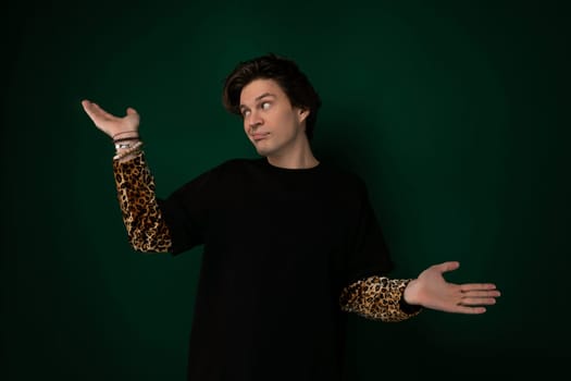 A man wearing a black shirt is standing with his arms outstretched. He appears to be in a posture of openness or surrender, with his palms facing upwards. The background is simple and neutral, allowing the focus to be on the mans gesture.