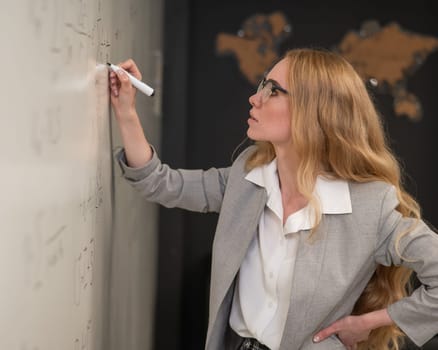 Young woman scientist writes formulas on a white board