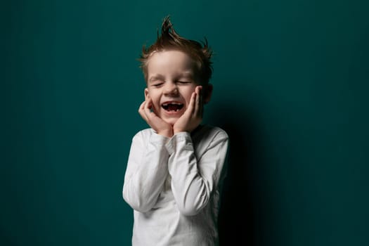 A young male child is standing in front of a vibrant green wall, looking straight ahead. He appears curious and engaged with his surroundings, with a slight smile on his face.