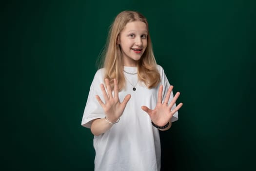 A woman is standing upright in front of a vibrant green background. She is the central focus of the composition, set against a solid green backdrop.