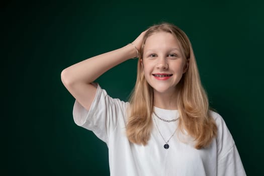 A young girl is striking a pose in front of a vibrant green background. She looks directly at the camera with a confident expression, showcasing her personality and style.