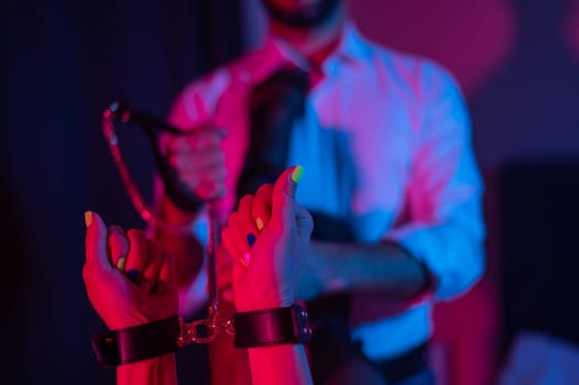 Sensual couple during role play. A man holds a woman by handcuffs. BDSM concept