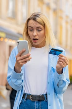 Shocked Caucasian woman trying to pay online shopping with smartphone blocked credit card. Annoyed lady tourist on street buying bank refuse problem unsuccessful payment lack of money balance bankrupt