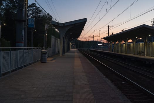 A beautiful railway station in the rays of a colorful sunset. Taking a picture using a wide-angle lens. High quality photo