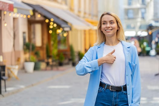 Like. Happy brunette woman tourist looking approvingly at camera showing double thumbs up positive something good positive feedback. Adult lady standing on urban city street. Town lifestyles outdoors