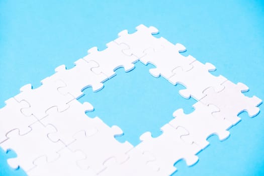 A puzzle piece is missing from a puzzle, leaving a gap in the middle. Concept of emptiness and incompleteness, as if something is missing from the puzzle. The blue background adds a calming