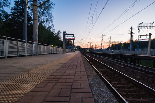 A beautiful railway station in the rays of a colorful sunset. Taking a picture using a wide-angle lens. High quality photo