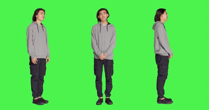 Young model doing no sign on camera, expressing negativity and disagreement over blank greenscreen backdrop. Asian person being displeased and disapproving with something, denial.