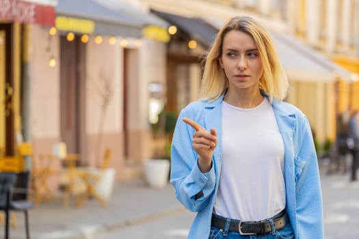 Displeased upset Caucasian woman reacting to unpleasant awful idea, dissatisfied with bad quality, wave hand, shake head No, dismiss idea, don't like proposal. Young adult lady traveler on city street