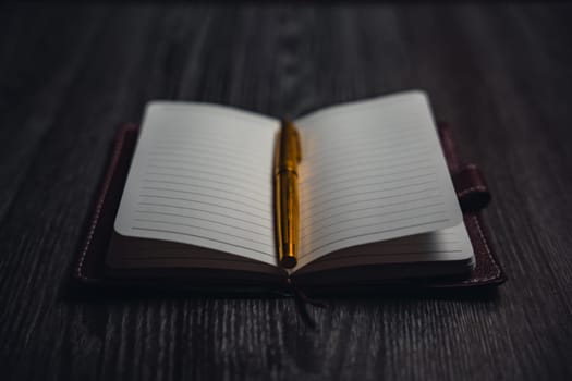 A notebook with a gold pen on the table in the candlelight. High quality photo