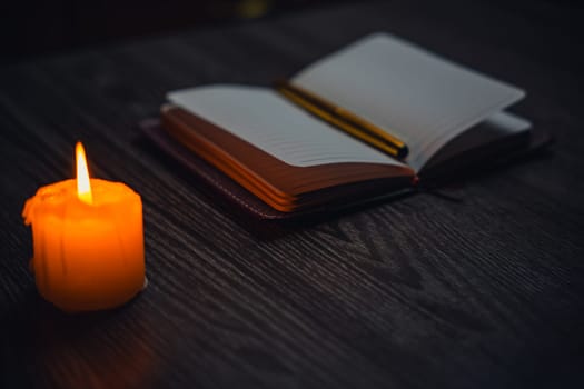 A notebook with a gold pen on the table in the candlelight. High quality photo