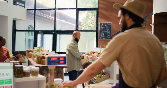 Young adult explores eco friendly store, browsing through variety of fresh organic pantry products with reusable packaging. Middle eastern customer looking at pasta and grains in bulk.