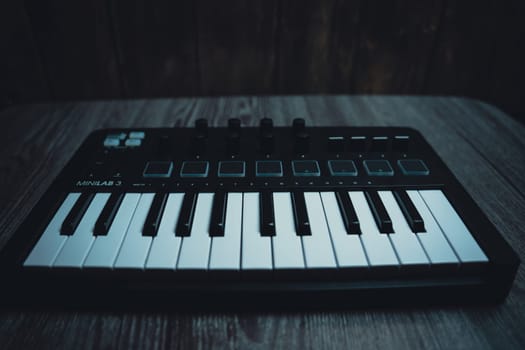 Black midi keyboard on a wooden table. Musical instrument. High quality photo