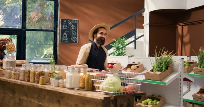 Small business owner arranging organic products on display, preparing local fresh produce supermarket merchandise for grocery shopping. Man growing fruits and veggies, ethically sourced.