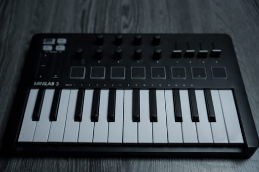 Black midi keyboard on a wooden table. Musical instrument. High quality photo