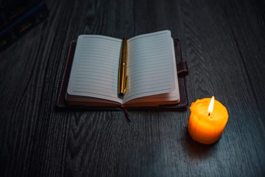 A notebook with a gold pen on the table in the candlelight. High quality photo