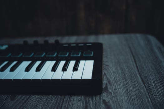 Black midi keyboard on a wooden table. Musical instrument. High quality photo