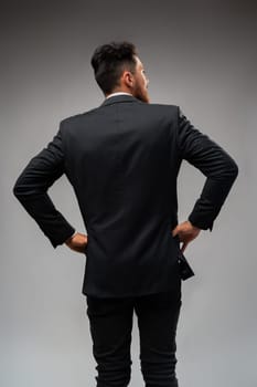 Young businessman from the back standing on gray background in studio