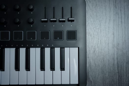 Black midi keyboard on a wooden table. Musical instrument. High quality photo