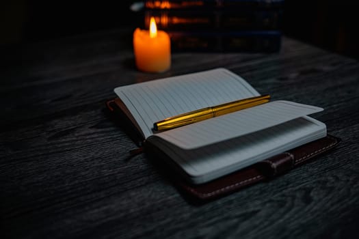 A notebook with a gold pen on the table in the candlelight. High quality photo