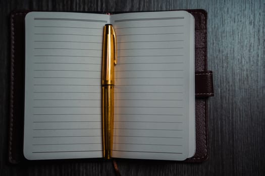 A notebook with a gold pen on the table in the candlelight. High quality photo