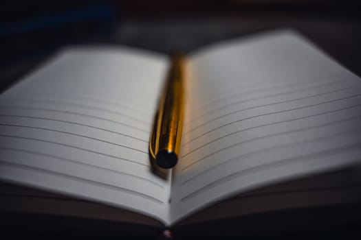 A notebook with a gold pen on the table in the candlelight. High quality photo