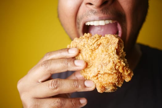 Man enjoying fried chicken, mouth open, savoring every bite with a big smile.