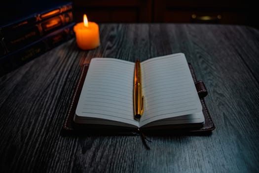 A notebook with a gold pen on the table in the candlelight. High quality photo