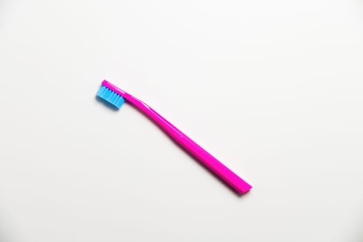 Hand toothbrush on a white background. Bright pink brush for cleaning teeth, top view.