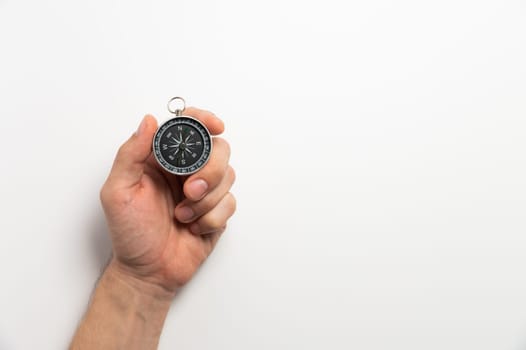 compass in hand on a white background close-up. male hand hold modern compass in retro style.