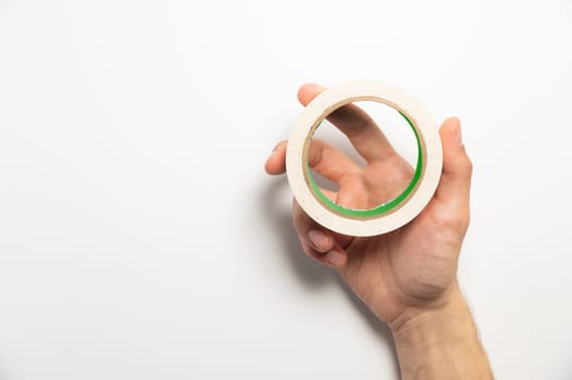 Hand holding adhesive tape on a white background. Molar tape in a man's hand, product demonstration.