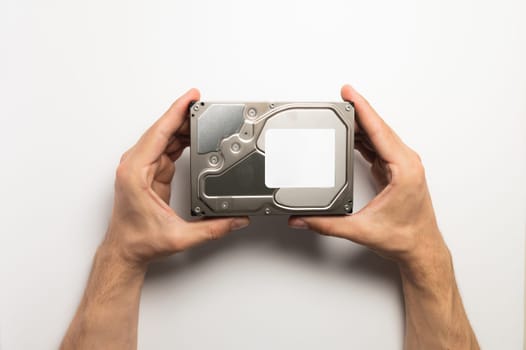 Man's hands showing a hard drive from a desktop computer close-up on a white background.