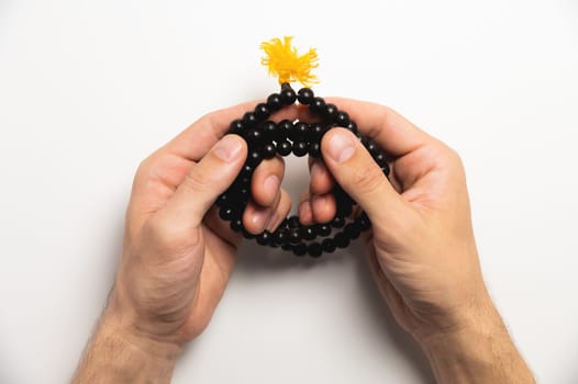 Selective focus, man's hands holding wooden rosary beads on white background.