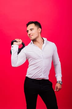 Attractive businessman Exercising With Kettlebell In a studio, red background