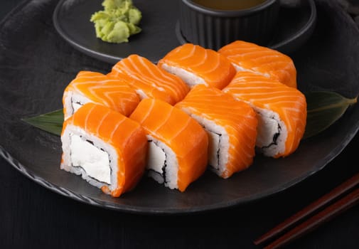 Philadelphia roll with salmon and cheese on plate on dark table.