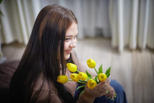 happy stylish fat plumb brunette girl with yellow tulips in room. happy young lady on International women's day, young hipster woman with present