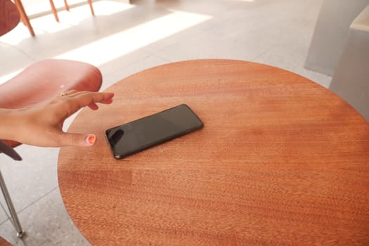 man hand picking up smart phone mobile from a table